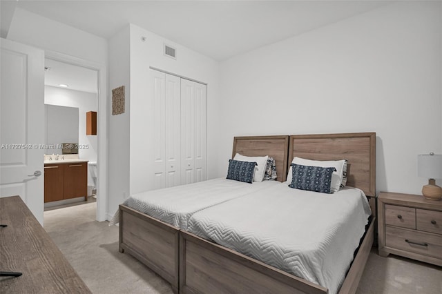 bedroom with sink, ensuite bath, a closet, and light carpet