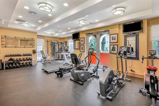 exercise room featuring a tray ceiling and french doors