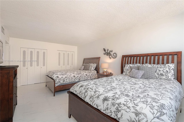 bedroom with multiple closets and a textured ceiling