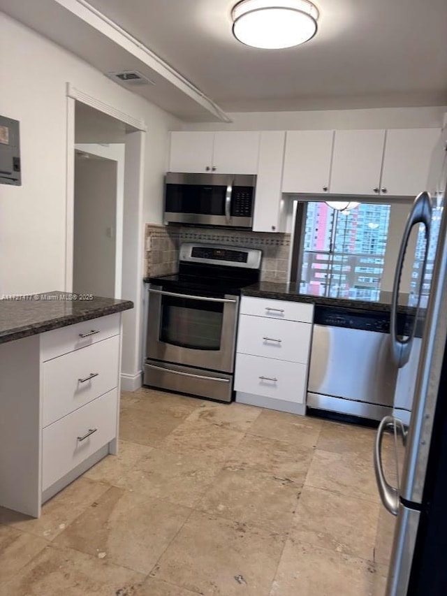 1401 NE Miami Gardens Dr Unit 892, Miami, FL 33179 - kitchen with appliances with stainless steel finishes, dark stone countertops, decorative backsplash, and white cabinets