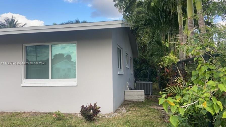 view of side of property with a yard and central AC unit