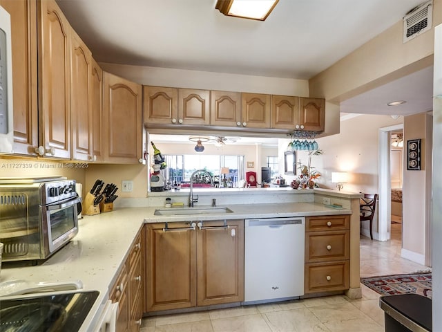 kitchen featuring light tile patterned floors, kitchen peninsula, ceiling fan, dishwasher, and sink