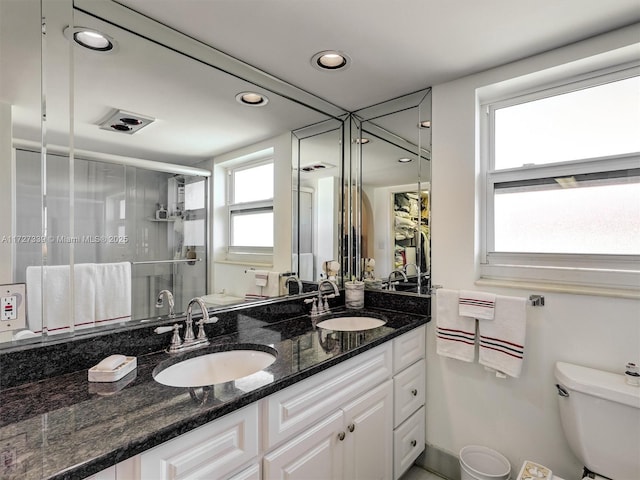 bathroom with walk in shower, vanity, and toilet