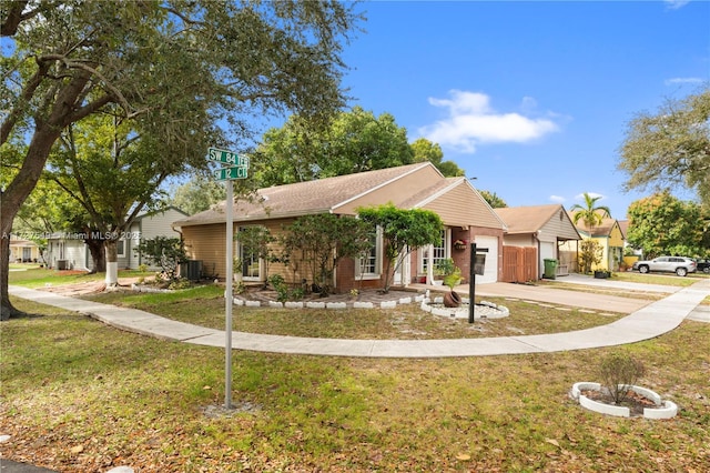 view of front facade with a garage, cooling unit, and a front lawn