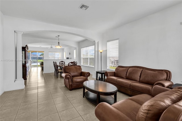 tiled living room featuring ceiling fan and decorative columns