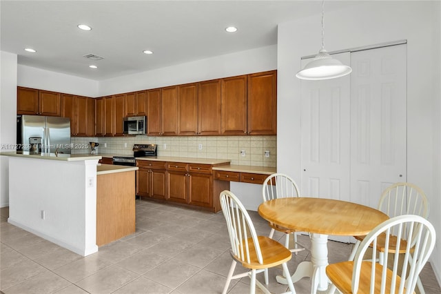 kitchen featuring backsplash, a kitchen island, pendant lighting, appliances with stainless steel finishes, and light tile patterned floors