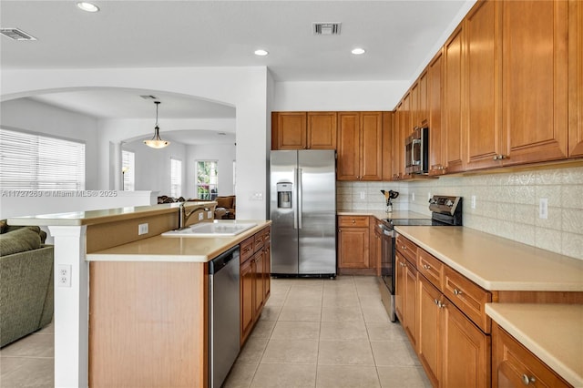 kitchen featuring stainless steel appliances, decorative backsplash, sink, hanging light fixtures, and light tile patterned flooring