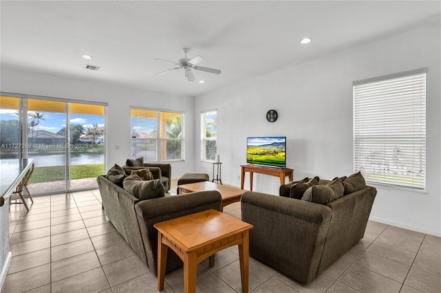 living room featuring ceiling fan, a water view, and light tile patterned flooring