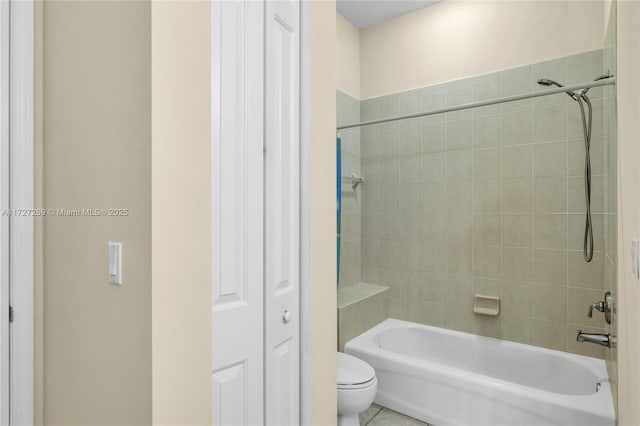 bathroom with toilet, tiled shower / bath combo, and tile patterned floors