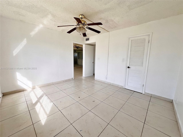 spare room with ceiling fan, a textured ceiling, and light tile patterned floors