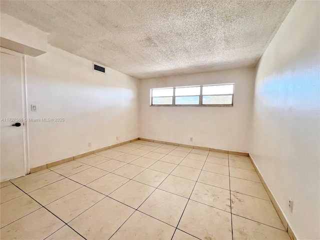 tiled empty room featuring a textured ceiling