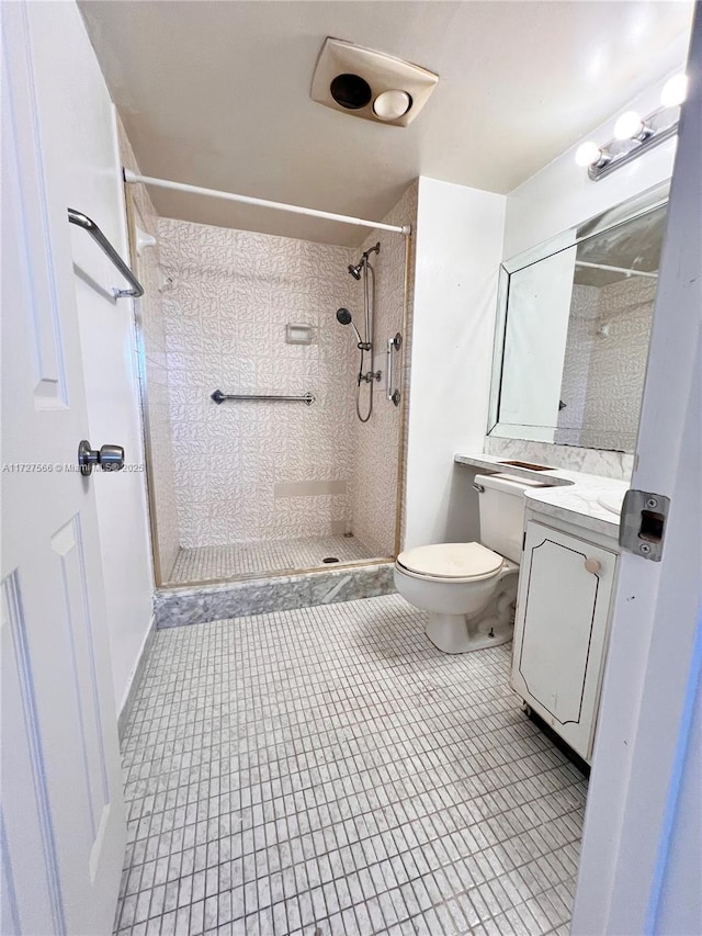 bathroom featuring toilet, vanity, tile patterned flooring, and tiled shower