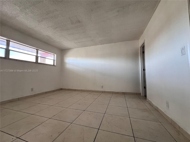 empty room featuring light tile patterned floors and a textured ceiling