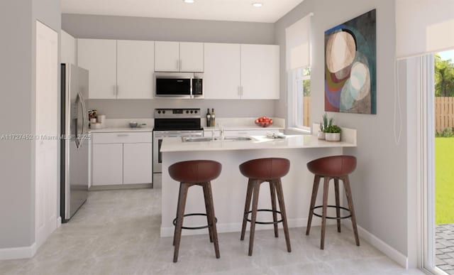 kitchen with a breakfast bar area, appliances with stainless steel finishes, kitchen peninsula, and white cabinets