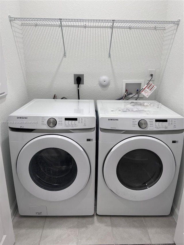 clothes washing area featuring washer and clothes dryer and light tile patterned flooring