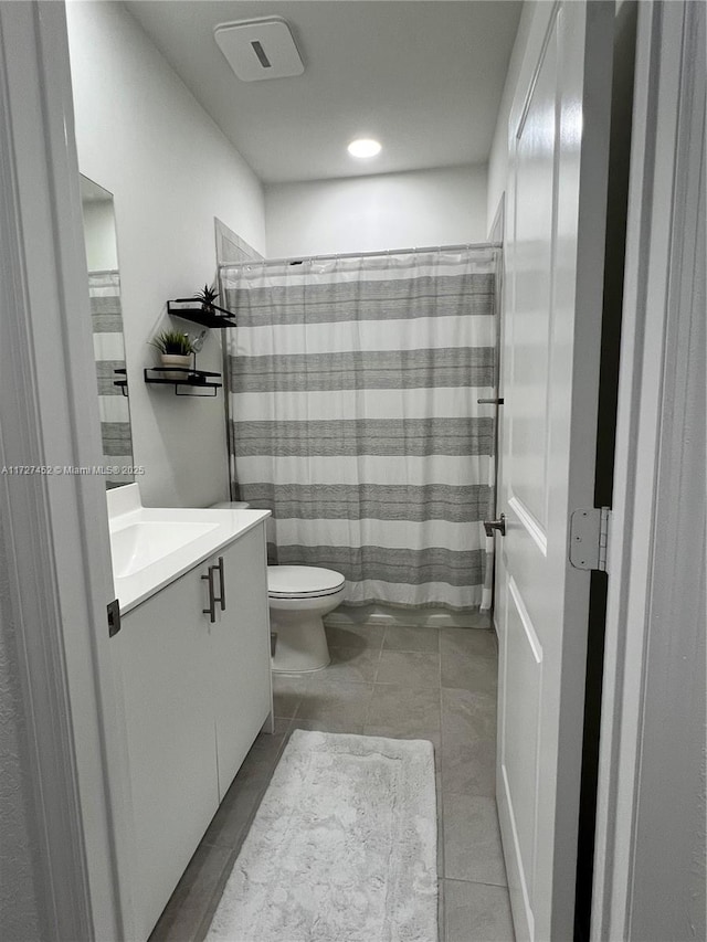 bathroom featuring toilet, vanity, tile patterned flooring, and walk in shower