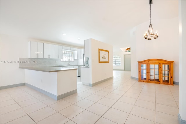 kitchen featuring tasteful backsplash, a notable chandelier, pendant lighting, kitchen peninsula, and white cabinets