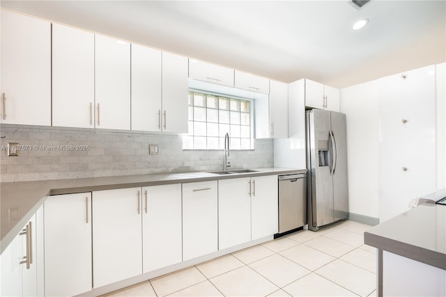 kitchen with backsplash, sink, light tile patterned floors, appliances with stainless steel finishes, and white cabinets