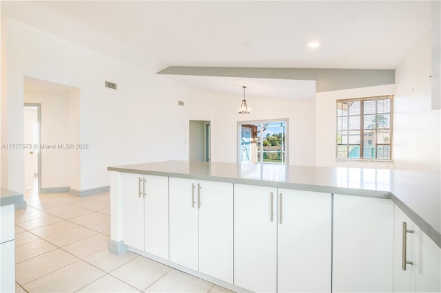 kitchen featuring lofted ceiling, white cabinets, light tile patterned floors, and hanging light fixtures