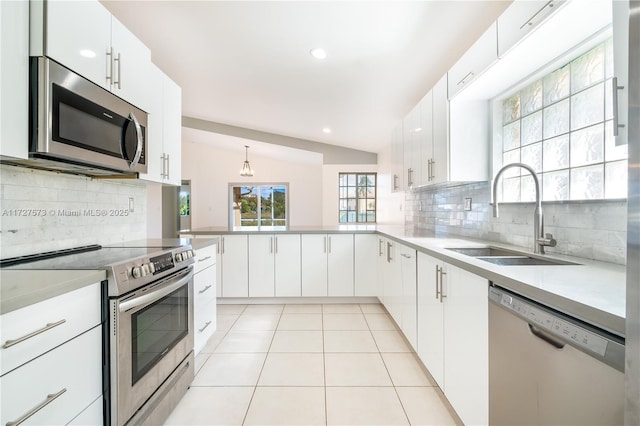 kitchen with sink, white cabinetry, appliances with stainless steel finishes, and lofted ceiling