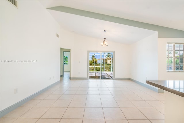 empty room featuring lofted ceiling and light tile patterned flooring