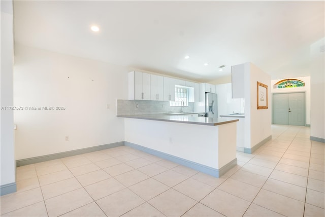 kitchen featuring white cabinetry, backsplash, stainless steel fridge with ice dispenser, kitchen peninsula, and light tile patterned flooring