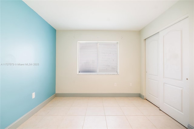 unfurnished bedroom featuring light tile patterned floors and a closet