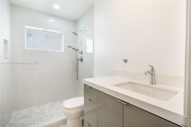 bathroom featuring toilet, a tile shower, and vanity