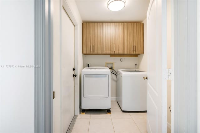 laundry area featuring washer and clothes dryer, cabinets, and light tile patterned floors