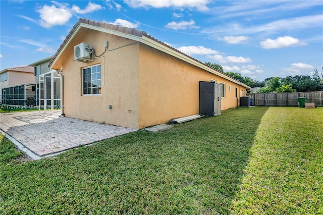 rear view of house featuring a patio area, central air condition unit, a lawn, and a wall mounted air conditioner