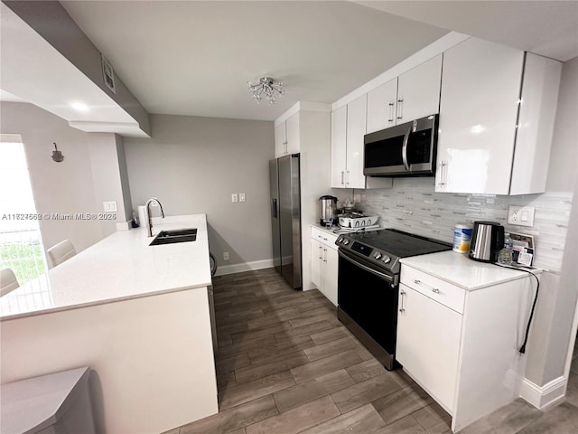 kitchen with white cabinets, stainless steel appliances, sink, kitchen peninsula, and a chandelier