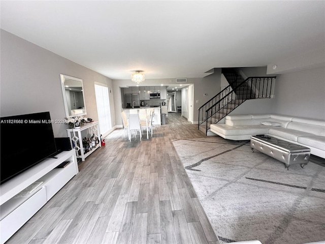 living room with a notable chandelier and light wood-type flooring