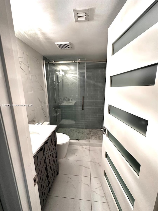 bathroom with a shower with shower door, toilet, and vanity