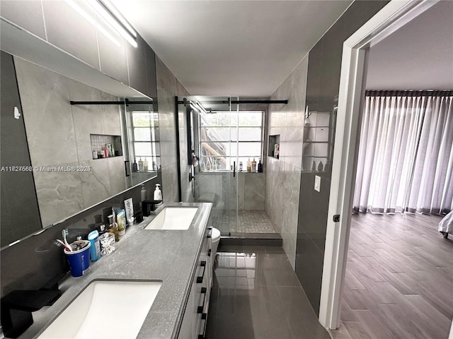 bathroom featuring hardwood / wood-style floors, vanity, tile walls, toilet, and a shower with shower door