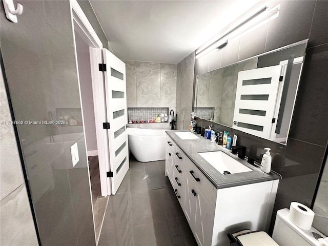 bathroom featuring vanity, tile patterned flooring, tile walls, a bath, and decorative backsplash