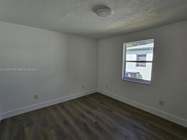 empty room featuring dark wood-type flooring and a textured ceiling