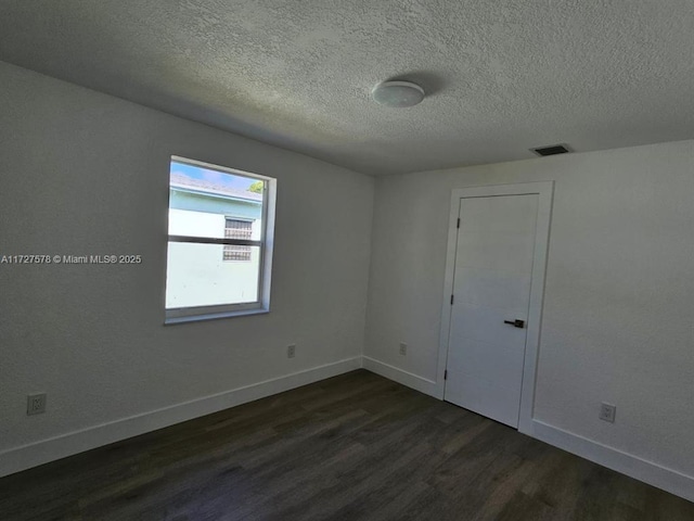 empty room featuring dark hardwood / wood-style floors and a textured ceiling