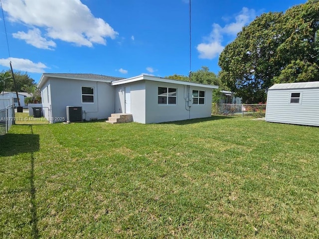 back of house featuring cooling unit, a shed, and a lawn