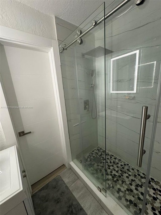 bathroom featuring a shower with door, tile patterned flooring, and vanity