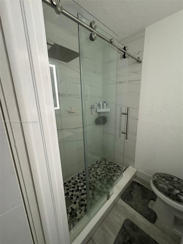 bathroom featuring a textured ceiling, an enclosed shower, and toilet