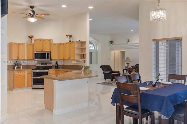 kitchen featuring kitchen peninsula, appliances with stainless steel finishes, light brown cabinetry, hanging light fixtures, and sink