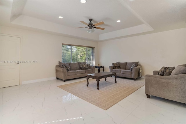 living room with ceiling fan and a tray ceiling