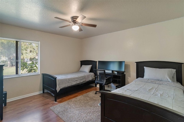 bedroom with ceiling fan, a textured ceiling, and hardwood / wood-style floors