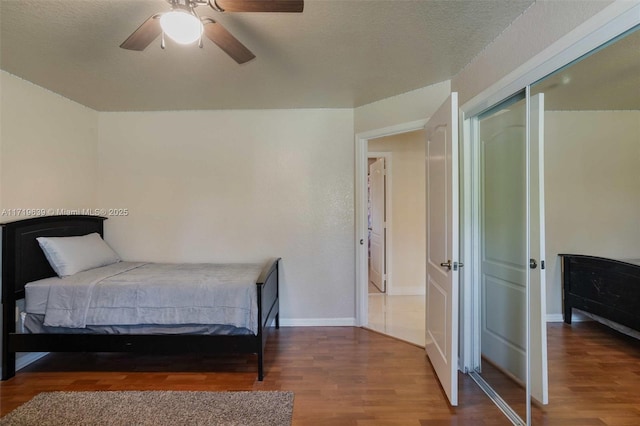 bedroom with a textured ceiling, ceiling fan, and hardwood / wood-style floors