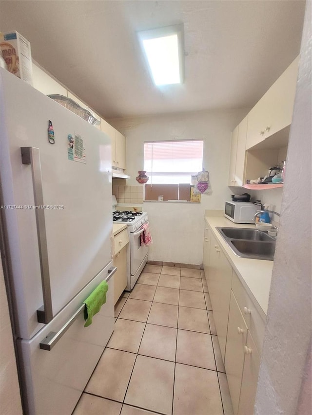 kitchen with backsplash, white appliances, light tile patterned flooring, white cabinets, and sink