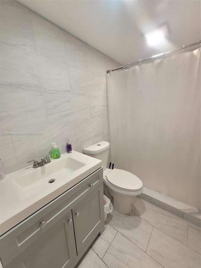 bathroom with tile patterned flooring, vanity, a shower with curtain, tile walls, and toilet