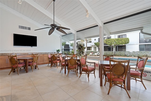 sunroom / solarium featuring ceiling fan, wood ceiling, a healthy amount of sunlight, and vaulted ceiling with beams