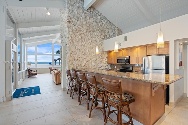 kitchen with appliances with stainless steel finishes, a kitchen breakfast bar, kitchen peninsula, a water view, and high vaulted ceiling