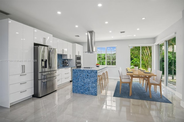 kitchen featuring white cabinetry, island range hood, a breakfast bar area, stainless steel appliances, and a kitchen island