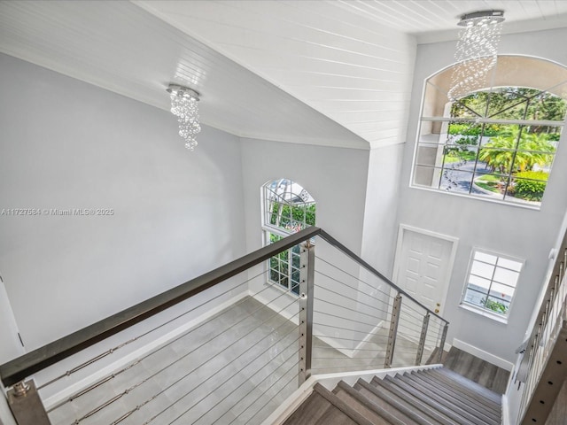 stairs featuring an inviting chandelier, ornamental molding, and wood-type flooring